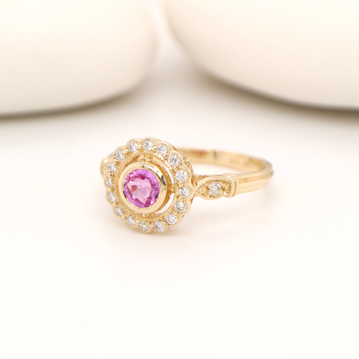 Pink sapphire with diamond halo in yellow gold ring