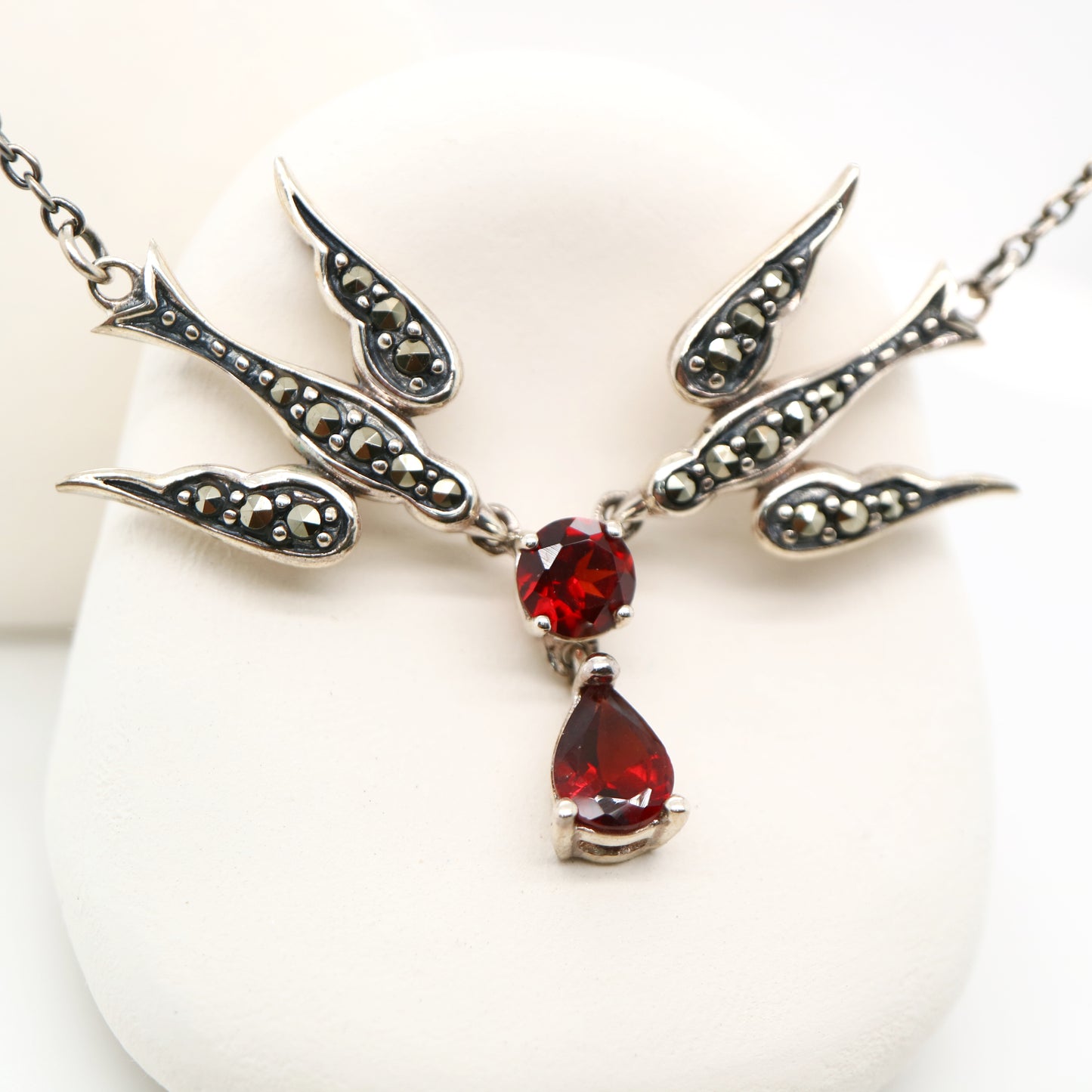Silver necklace with red gemstones on a white background