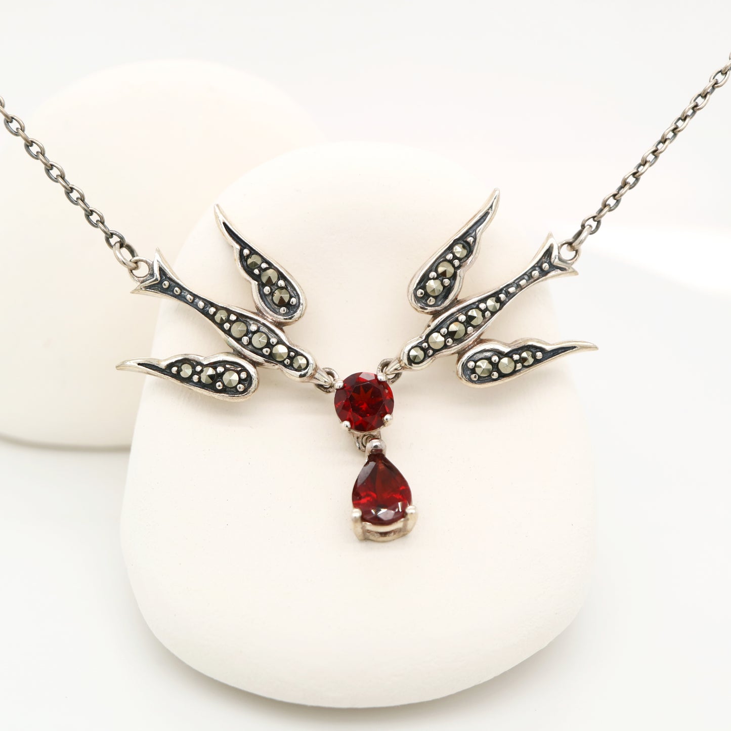 Silver necklace with red gemstones on a white background