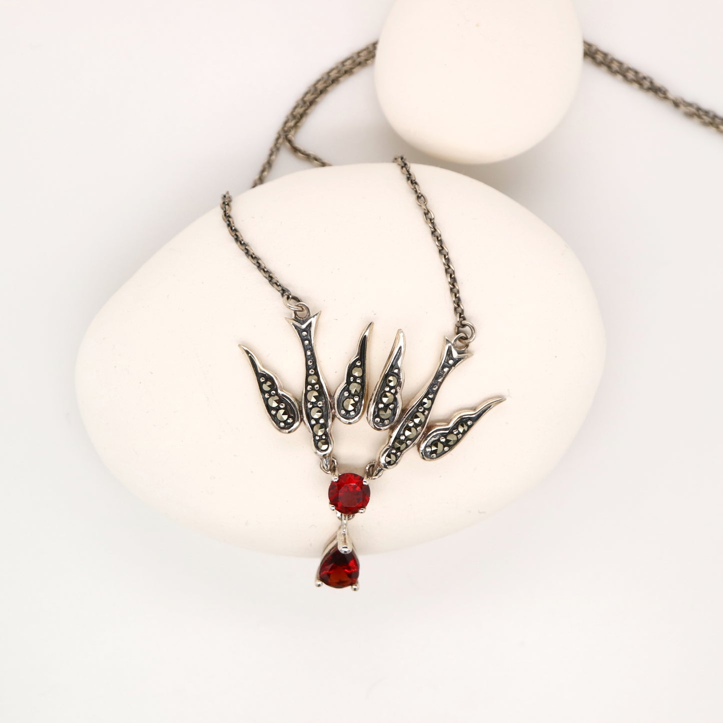 Necklace with red gemstone pendant on a white surface