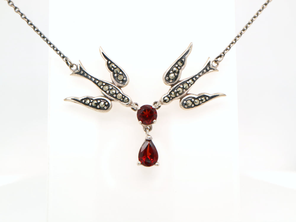 Necklace with a central red gemstone and bird designs on a white background