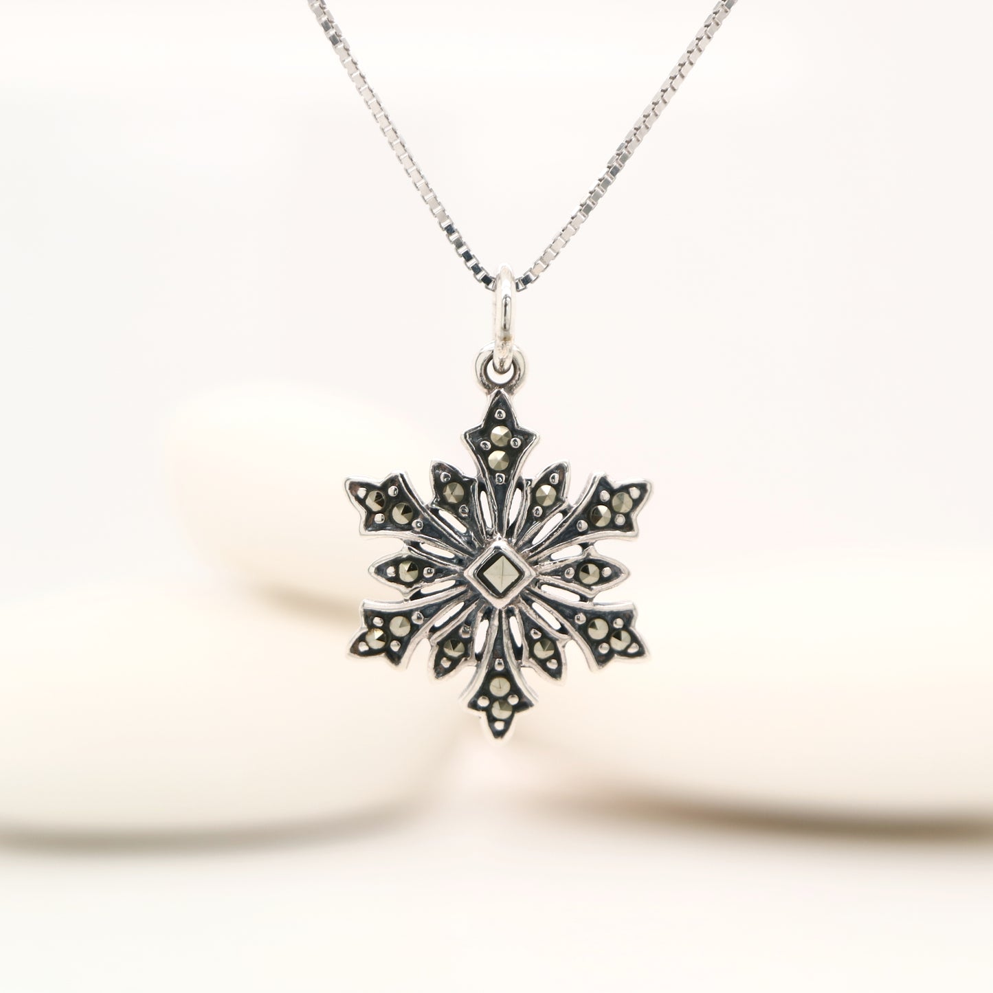 Silver snowflake pendant necklace on a white background