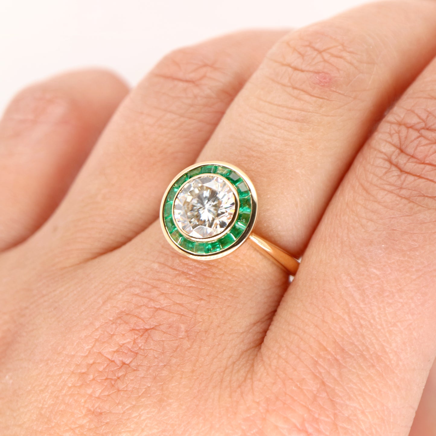 Moissanite with channel set emerald halo ring in yellow gold