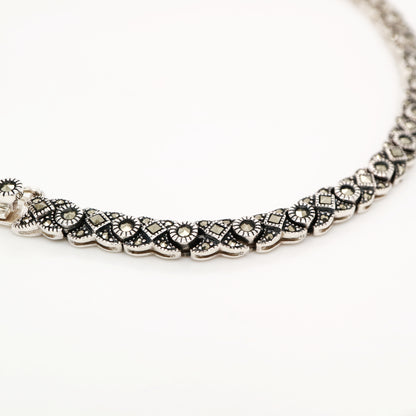 Silver necklace with floral patterns on a white background