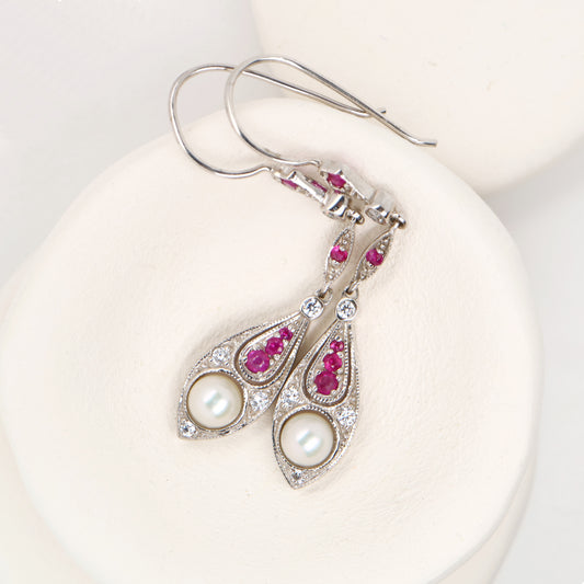 Silver earrings with pearls and red gemstones on a white background