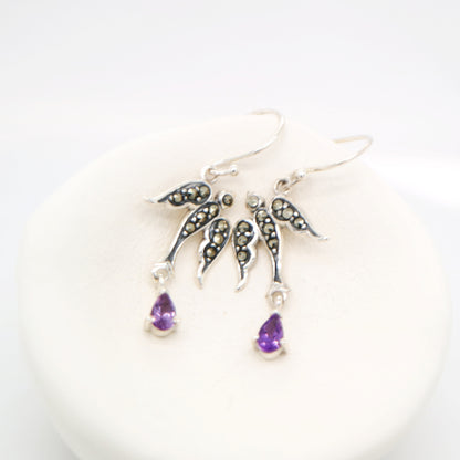 Silver earrings with purple teardrop charms on a white background