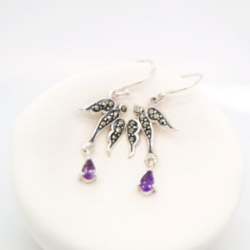 Silver earrings with purple teardrop charms on a white background
