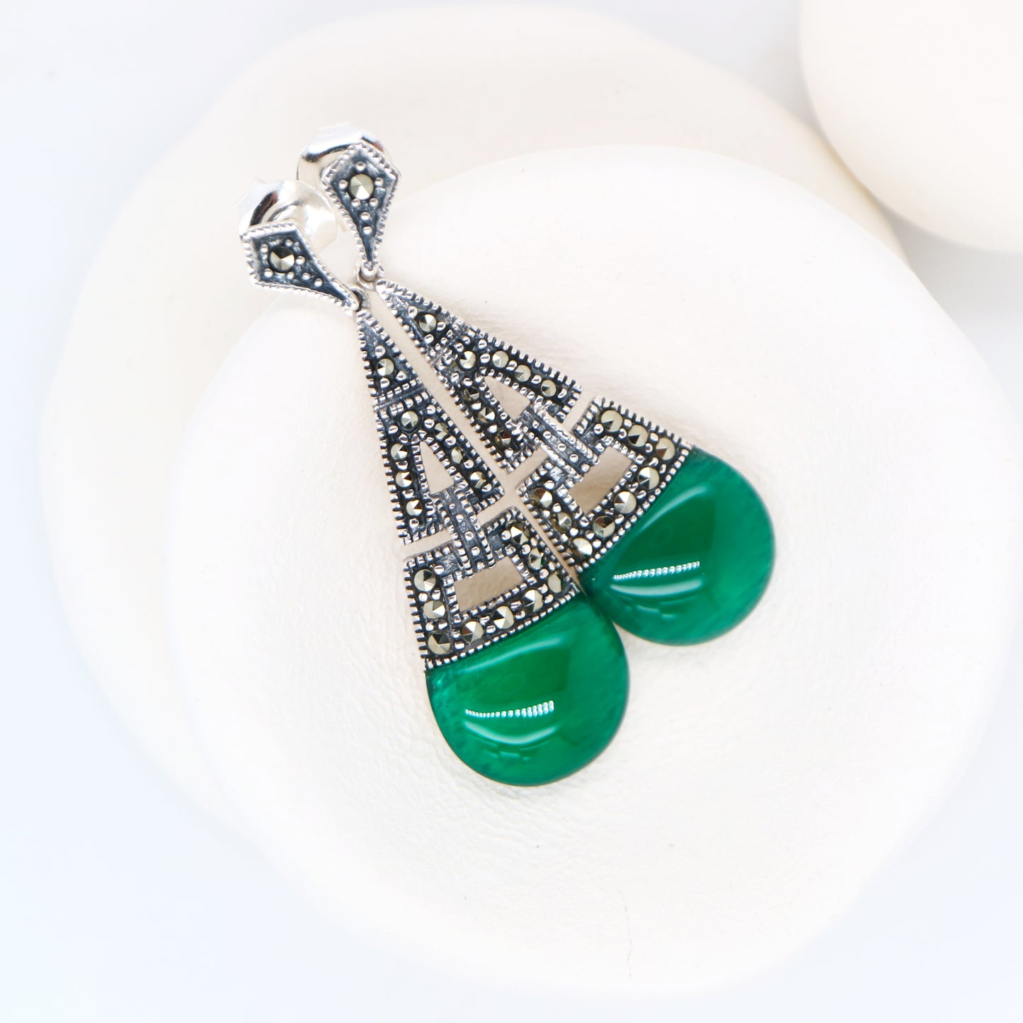 Green earring with decorative elements on a white background