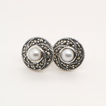 Pair of pearl earrings with decorative metalwork on a white background