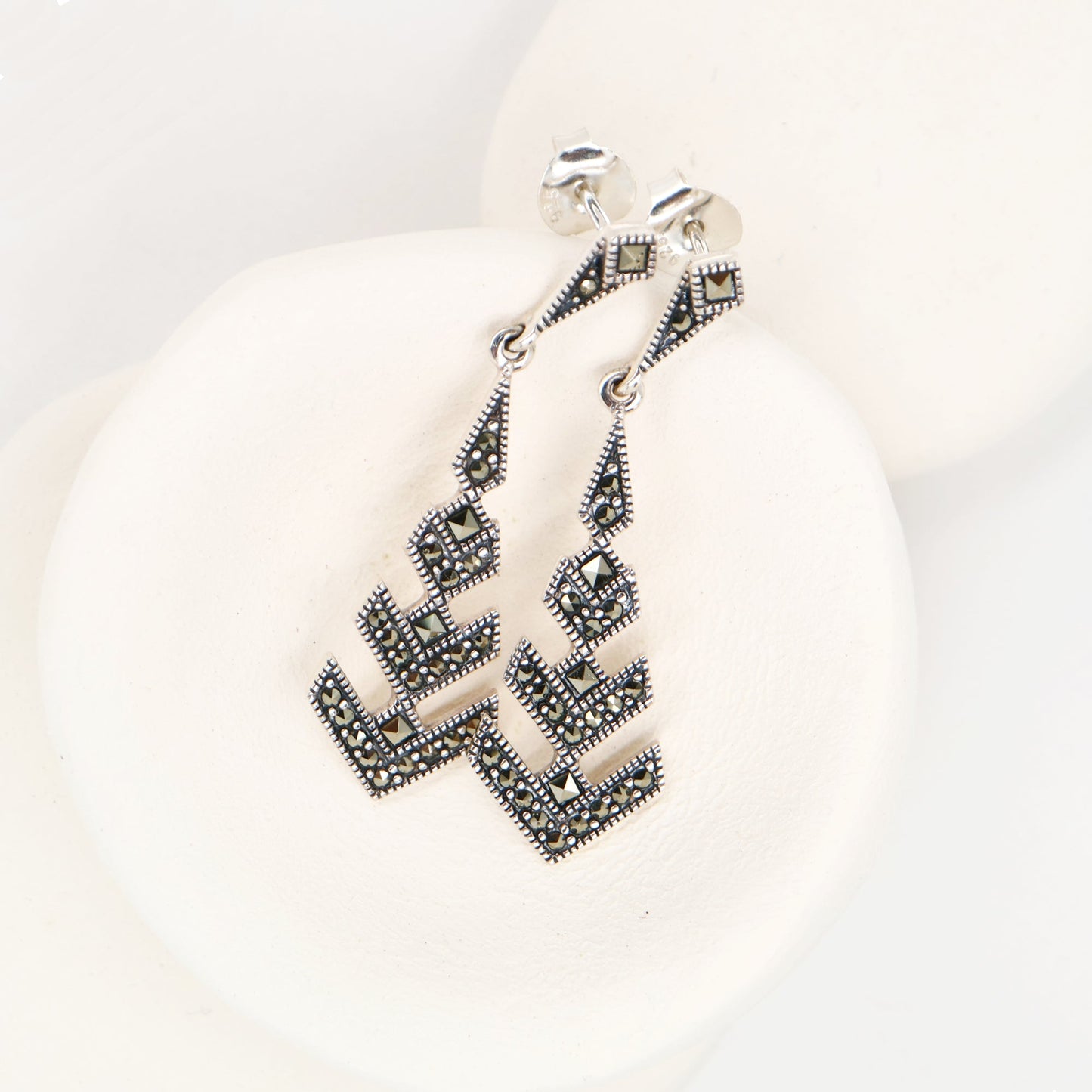 Silver earrings with geometric design on a white background