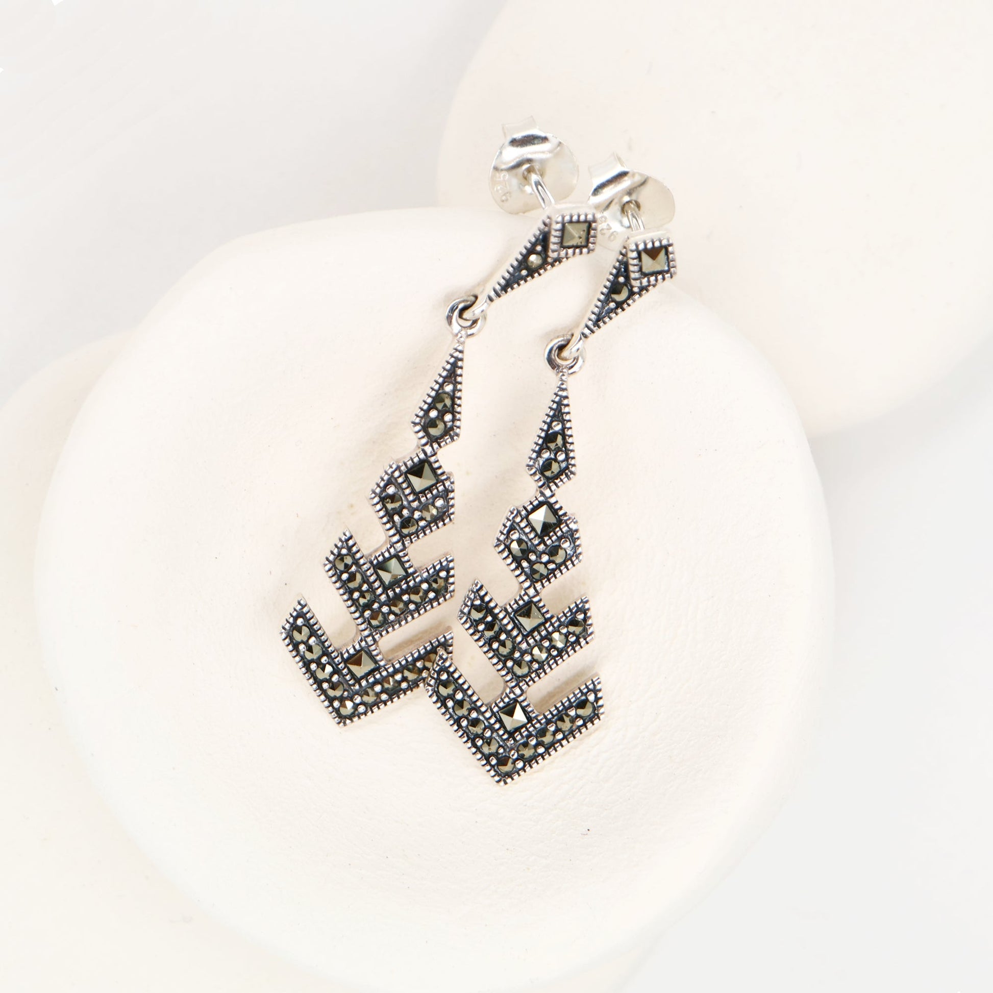 Silver earrings with geometric design on a white background