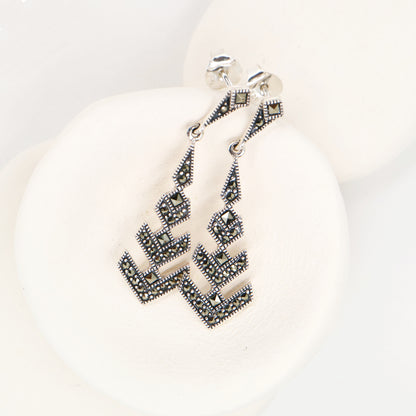 Pair of silver earrings with geometric design on a white background