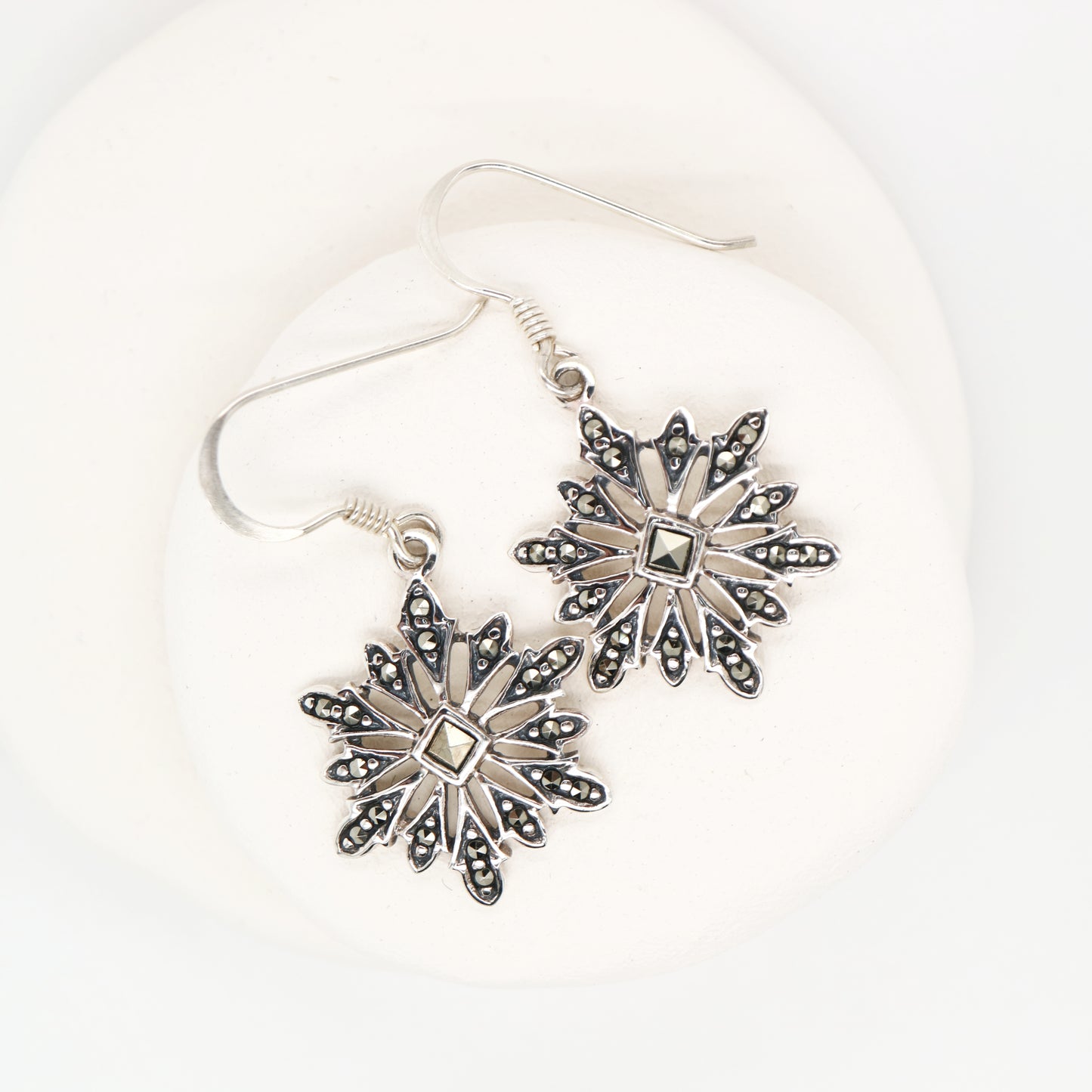 Silver snowflake earrings on a white background
