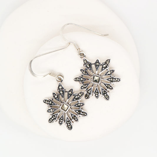 Silver snowflake earrings on a white background