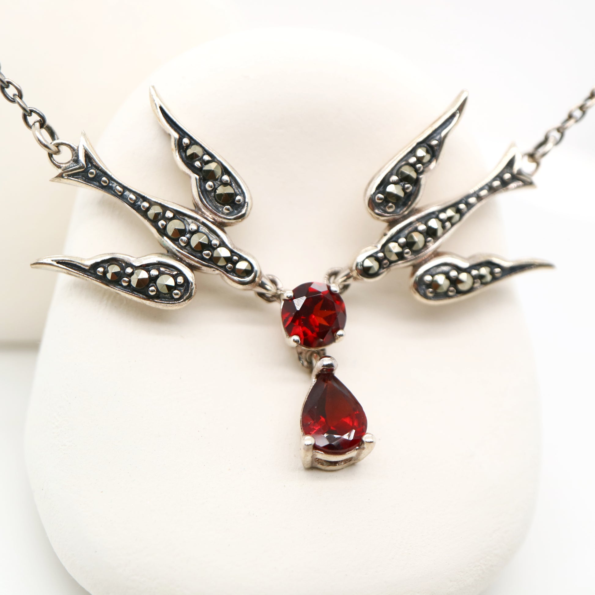 Silver necklace with red gemstones on a white background