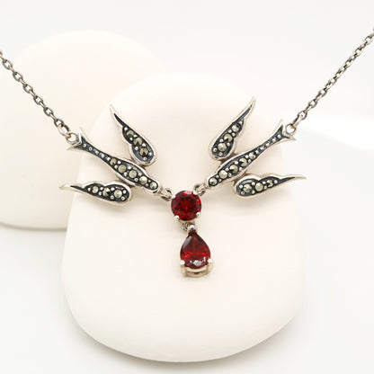 Silver necklace with red gemstones on a white background