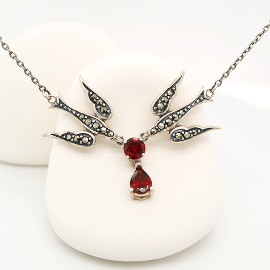 Silver necklace with red gemstones on a white background