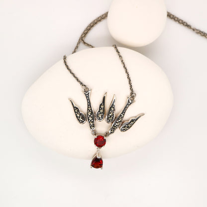 Necklace with red gemstone pendant on a white surface