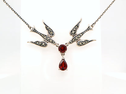 Necklace with a central red gemstone and bird designs on a white background