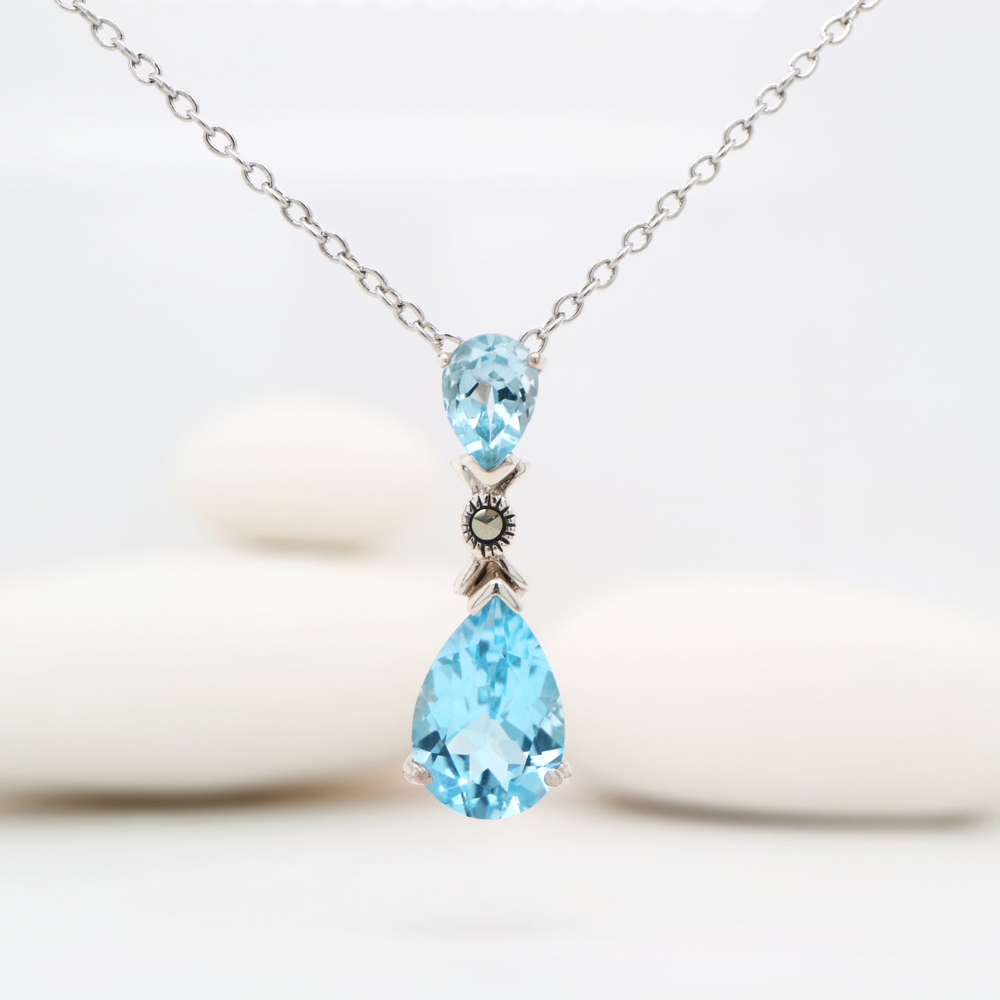 Necklace with two blue teardrop-shaped gemstones on a white background