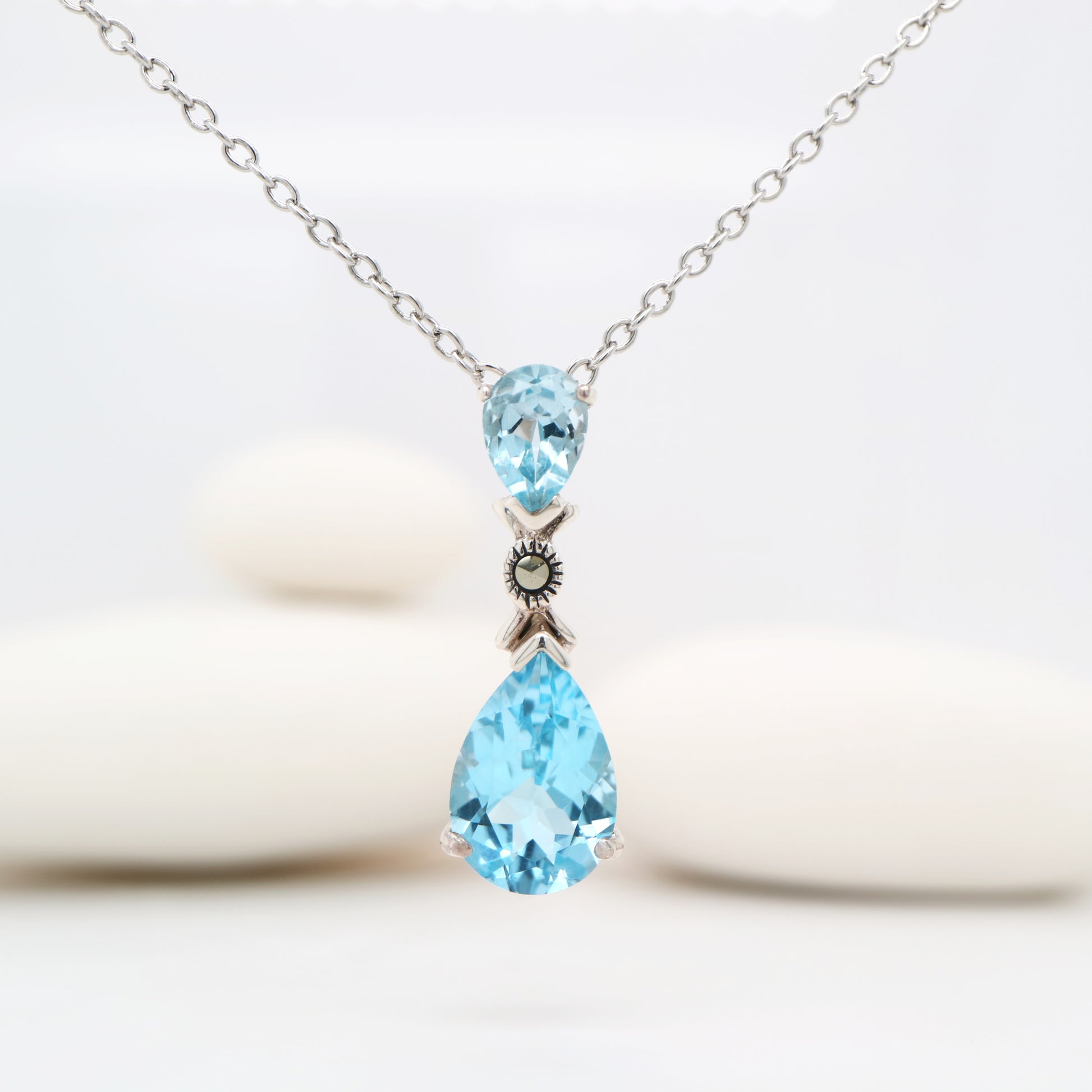 Necklace with two blue teardrop-shaped gemstones on a white background