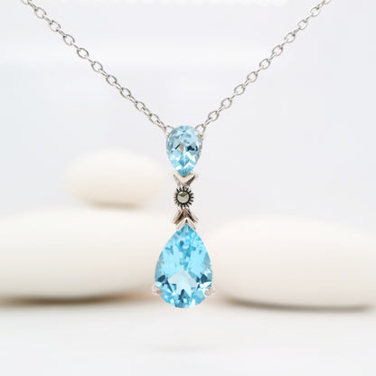 Necklace with two blue teardrop-shaped gemstones on a white background