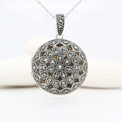 Silver necklace with a round, intricately designed pendant on a white background