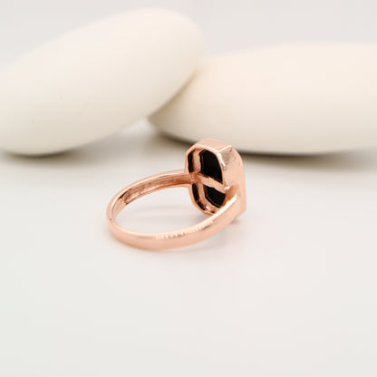 Rose gold ring with a black stone on a light background