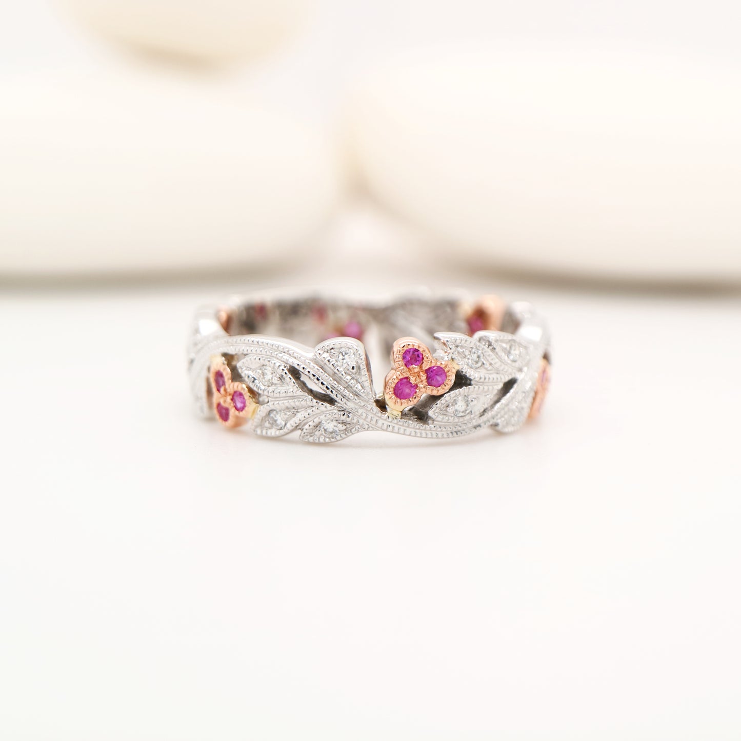 Silver ring with floral designs and gemstones on a white background
