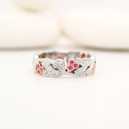 Silver ring with floral designs and gemstones on a white background