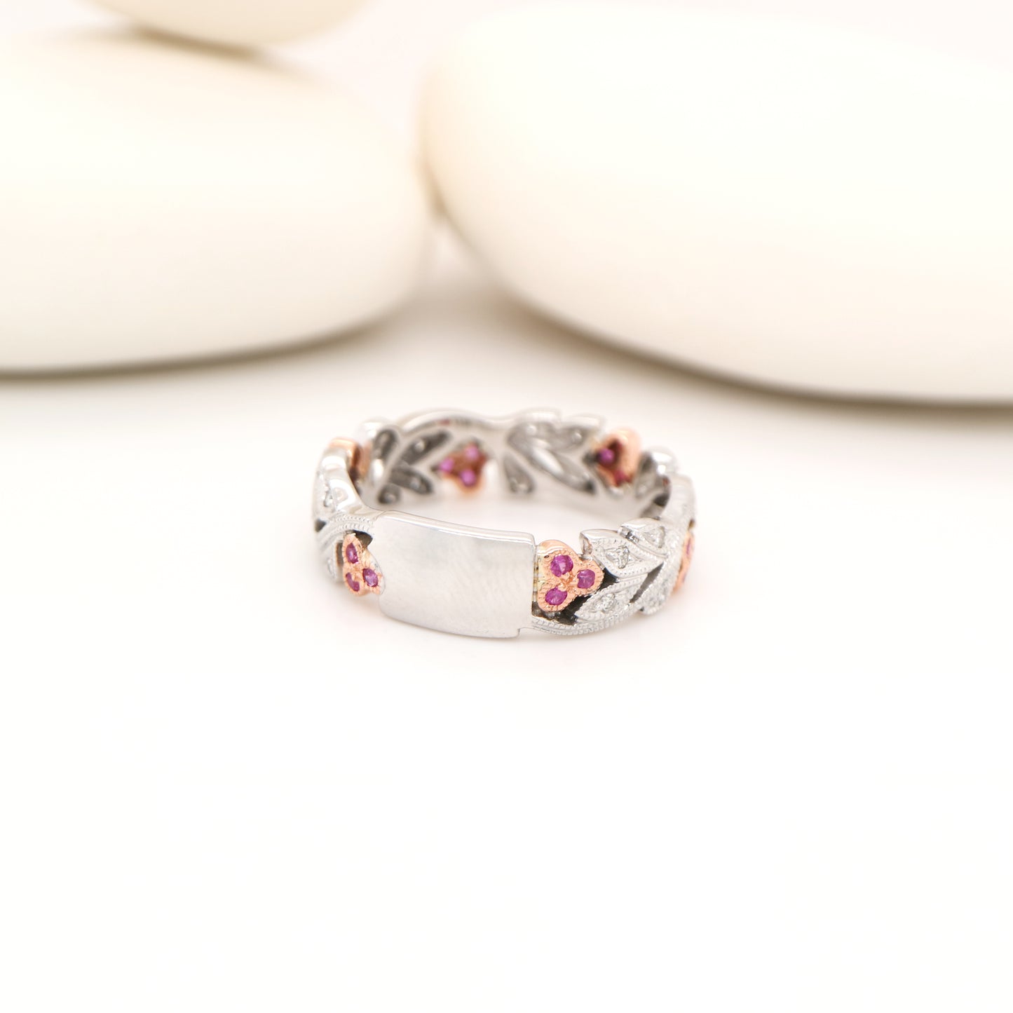 Silver ring with pink gemstones on a white background