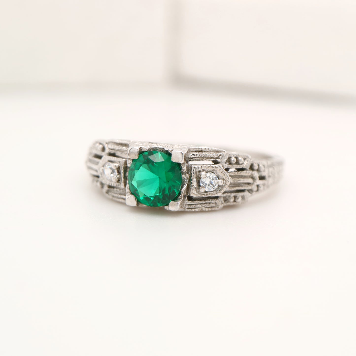 Art deco white gold ring with center emerald and shoulder diamond