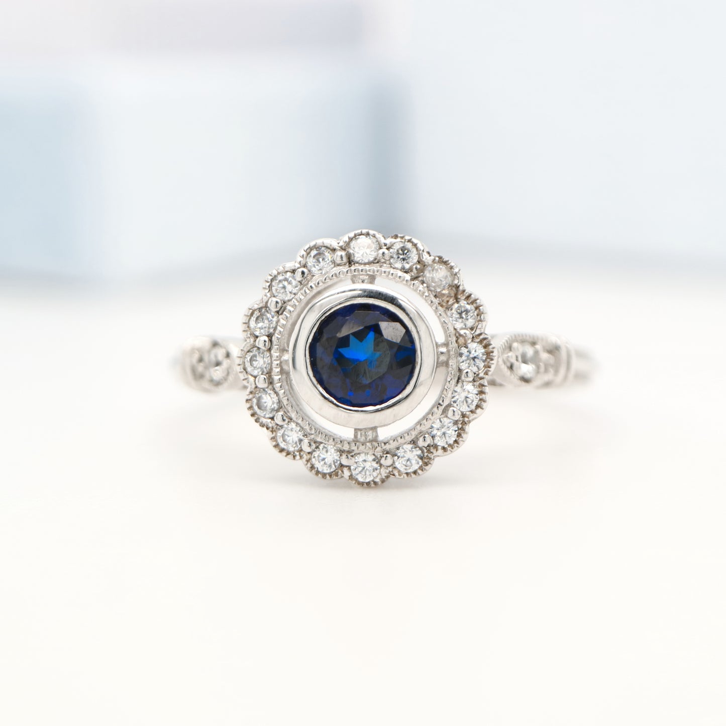 Laboratory grown blue sapphire with CZ halo in sterling silver ring