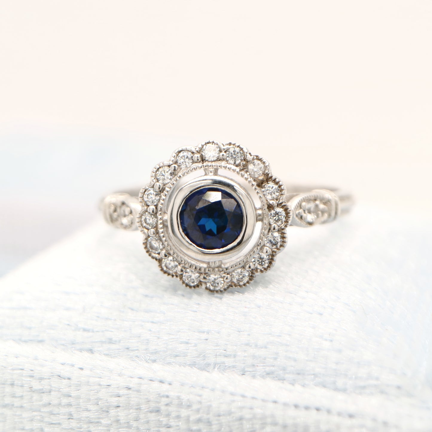 Laboratory grown blue sapphire with CZ halo in sterling silver ring