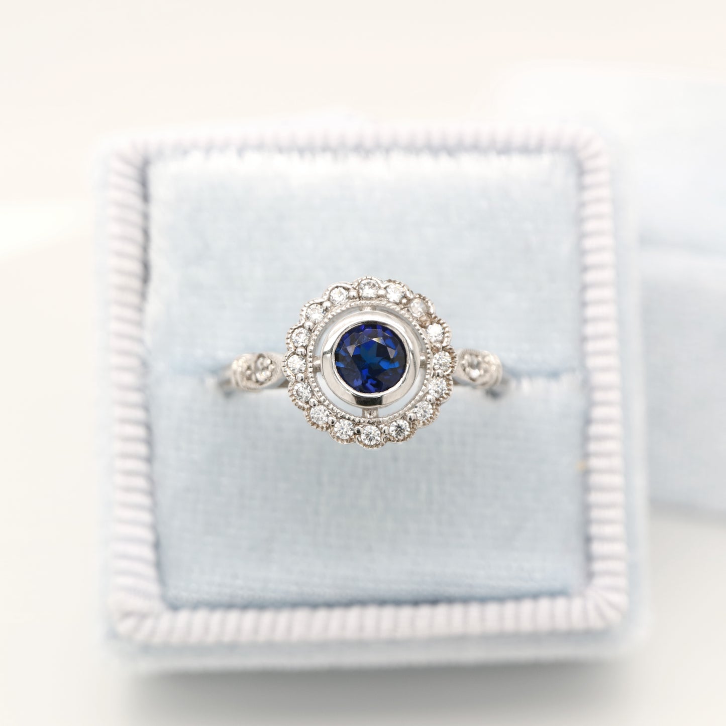 Laboratory grown blue sapphire with CZ halo in sterling silver ring