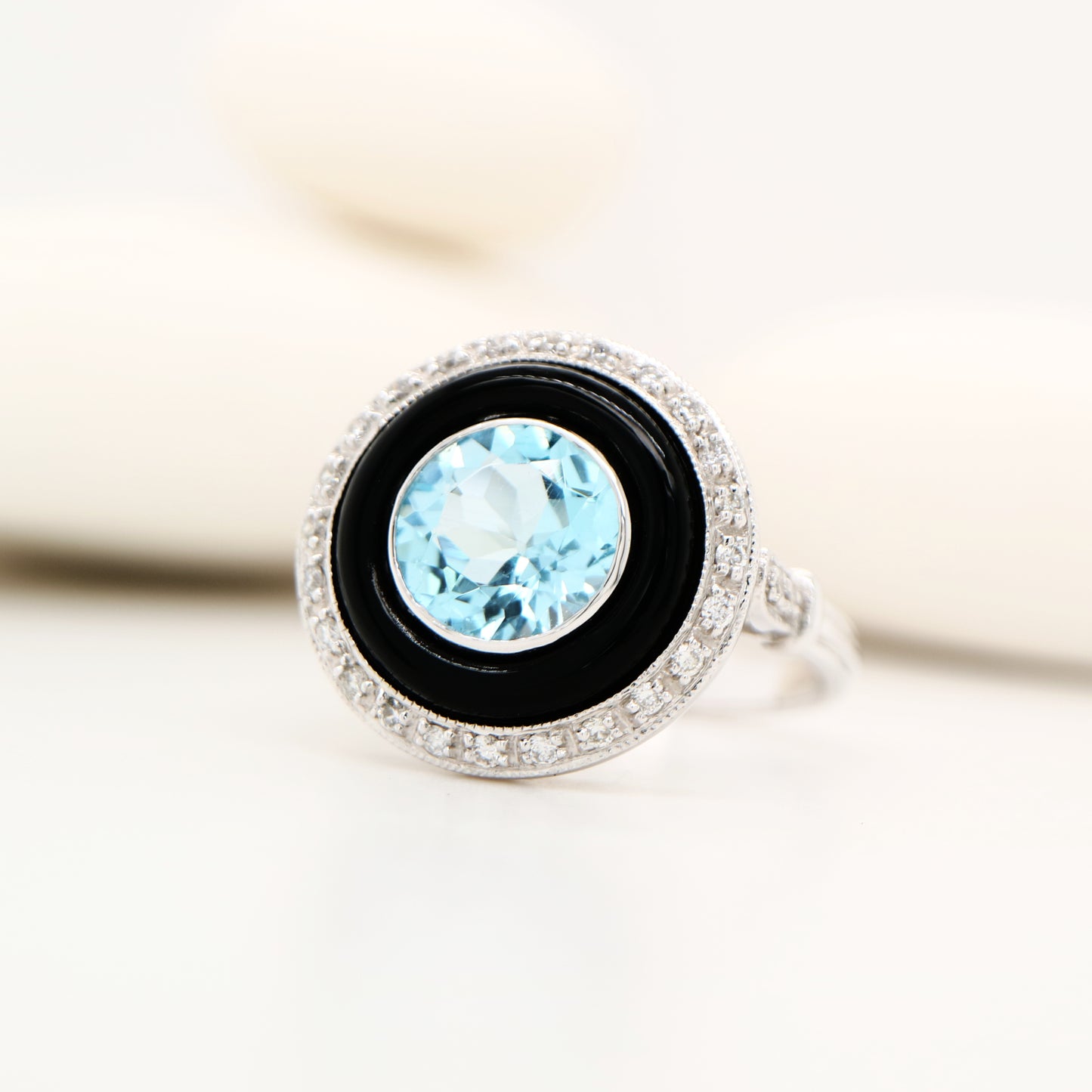 Round blue topaz ring with onyx and diamond halo in 9k white gold