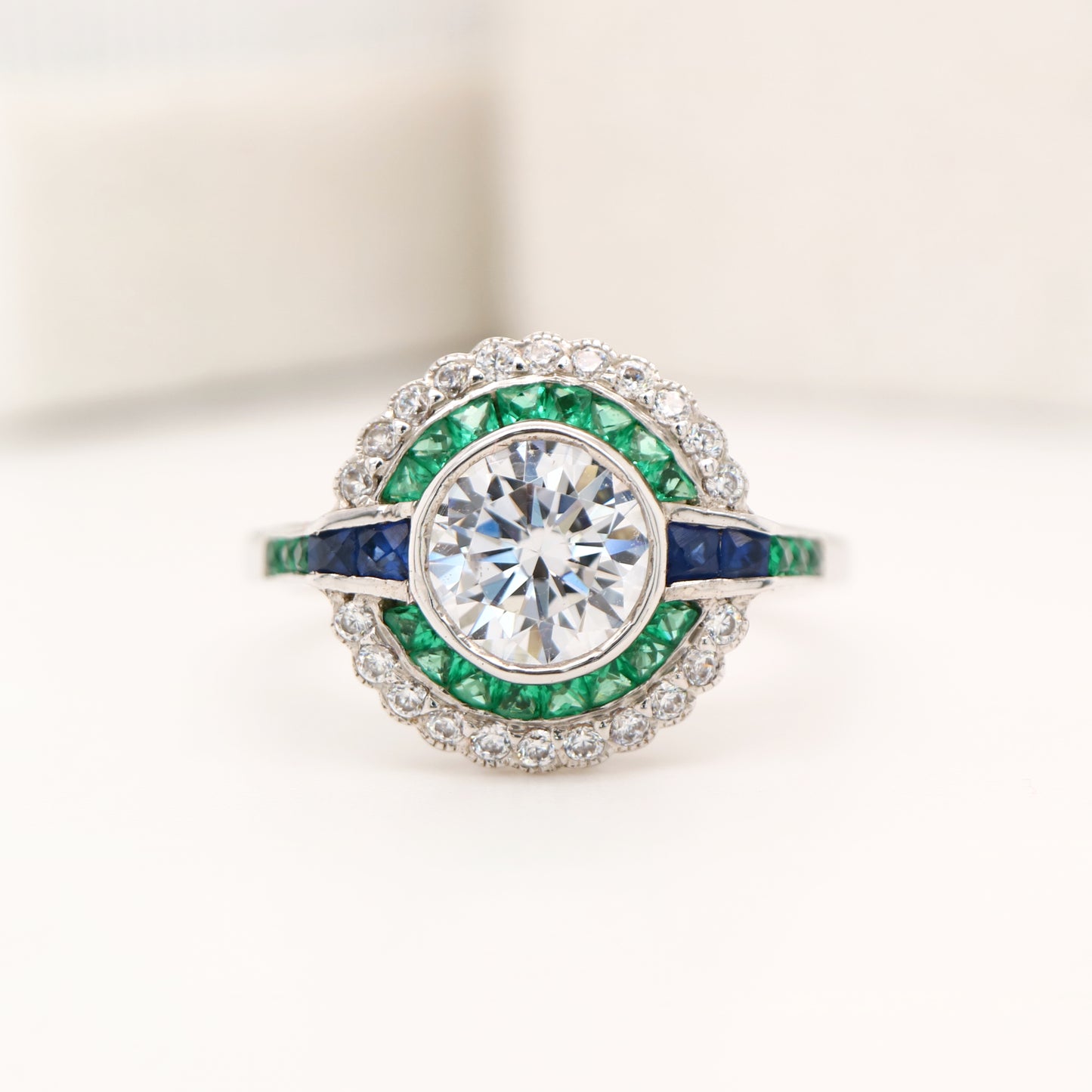 Moissanite and emerald target ring with sapphire accents in white gold