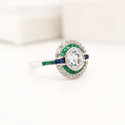 Moissanite and emerald target ring with sapphire accents in white gold