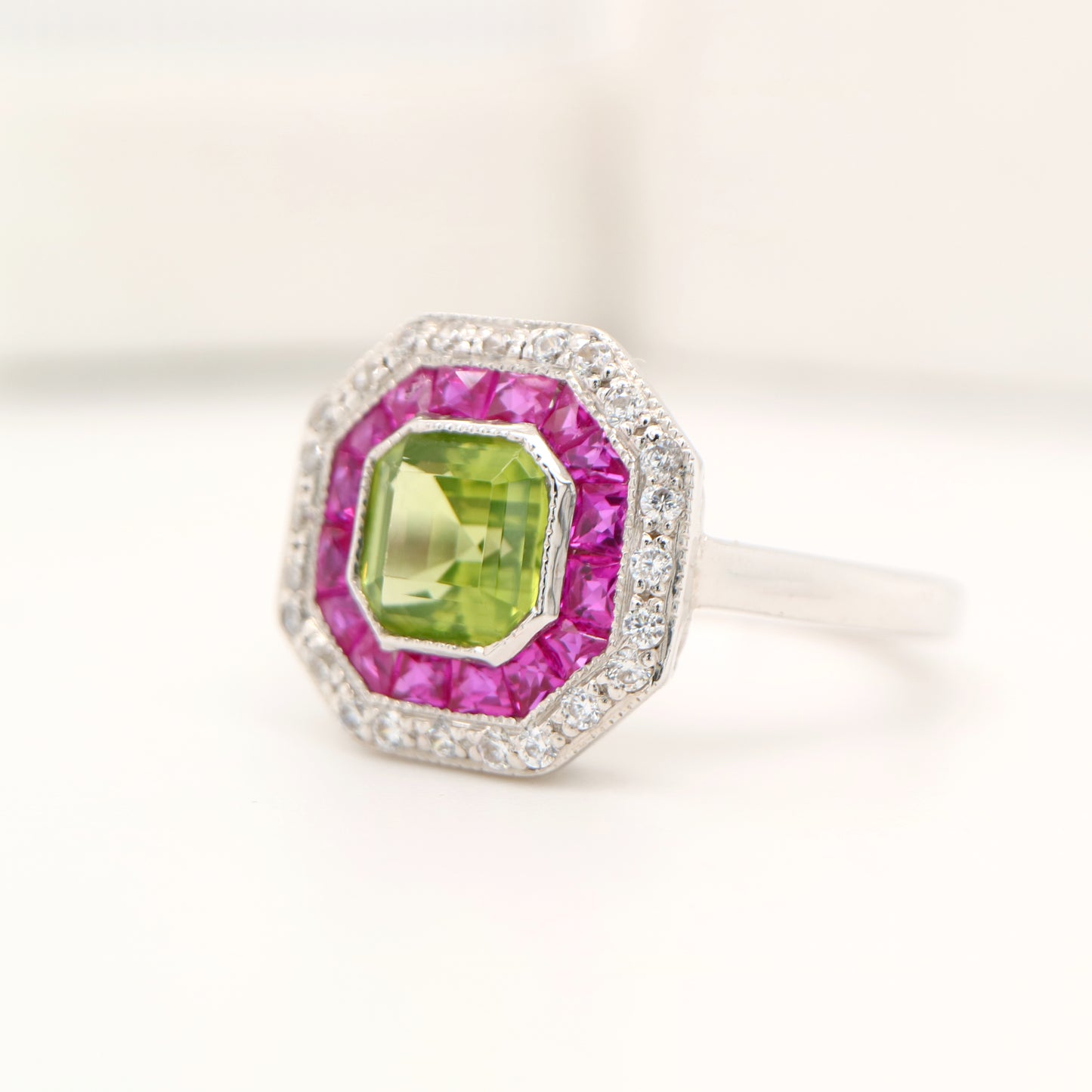Peridot target ring with ruby and diamond halo in white gold