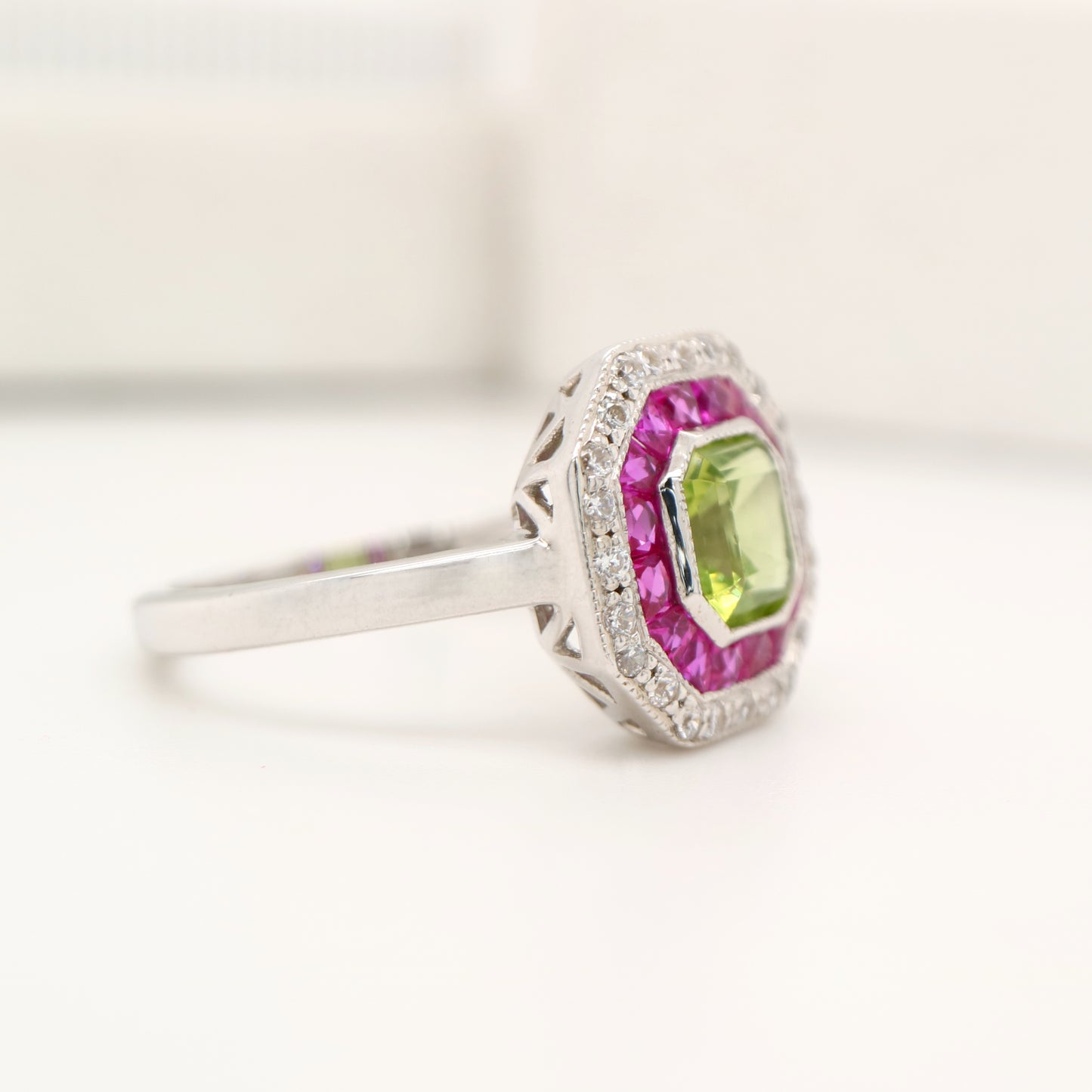 Peridot target ring with ruby and diamond halo in white gold