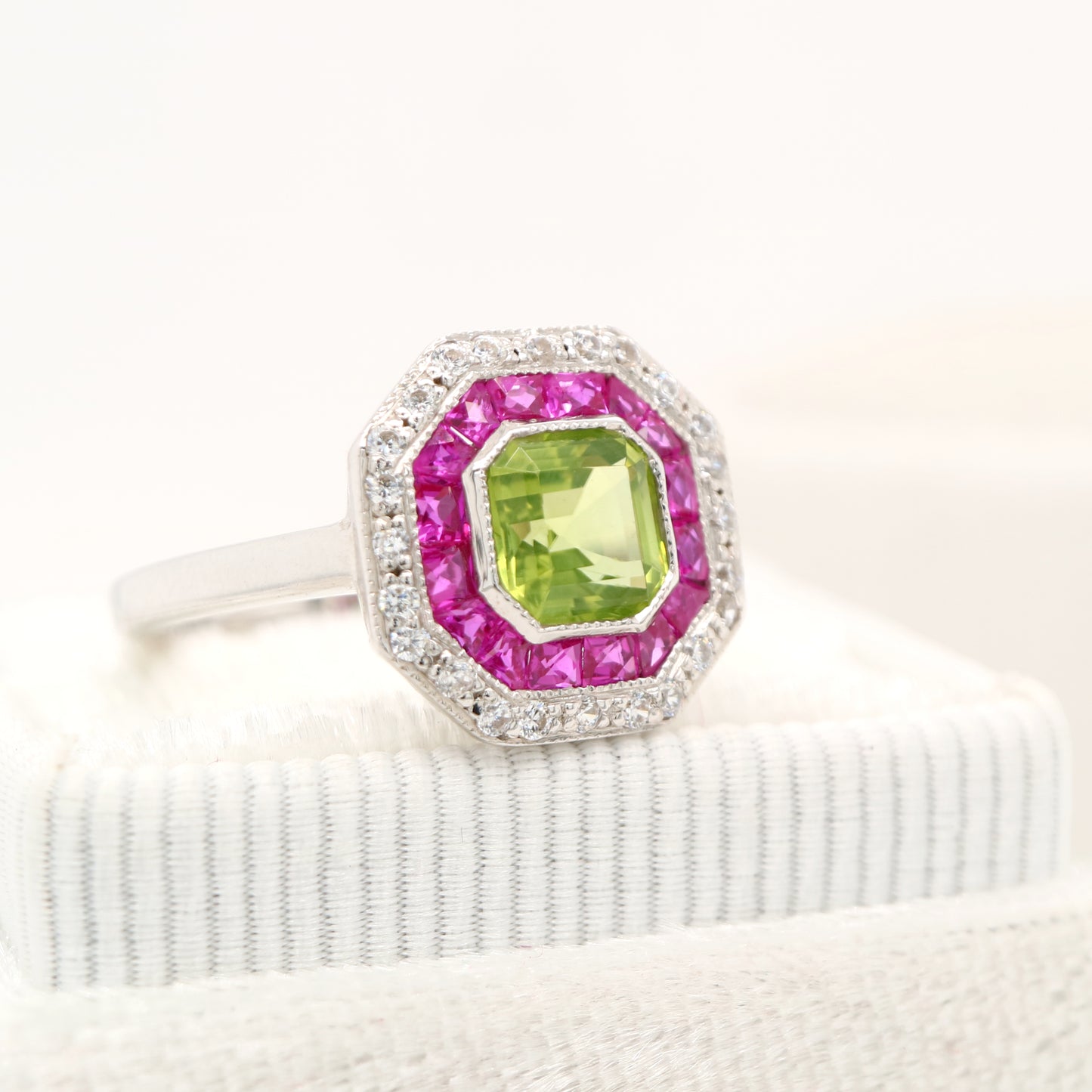 Peridot target ring with ruby and diamond halo in white gold