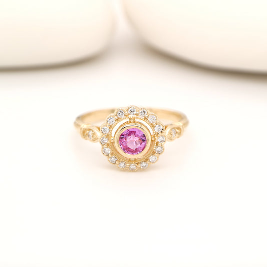 Gold ring with a pink gemstone on a light background