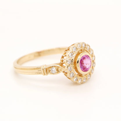 Gold ring with a pink gemstone and diamond accents on a white background