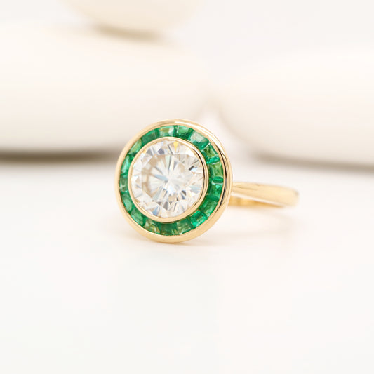 Moissanite with channel set emerald halo ring in yellow gold