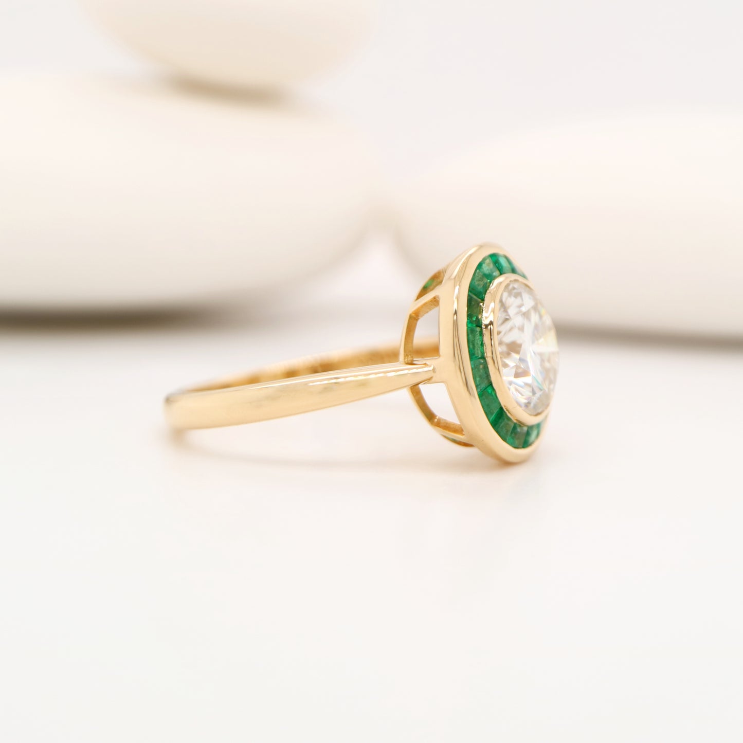 Moissanite with channel set emerald halo ring in yellow gold