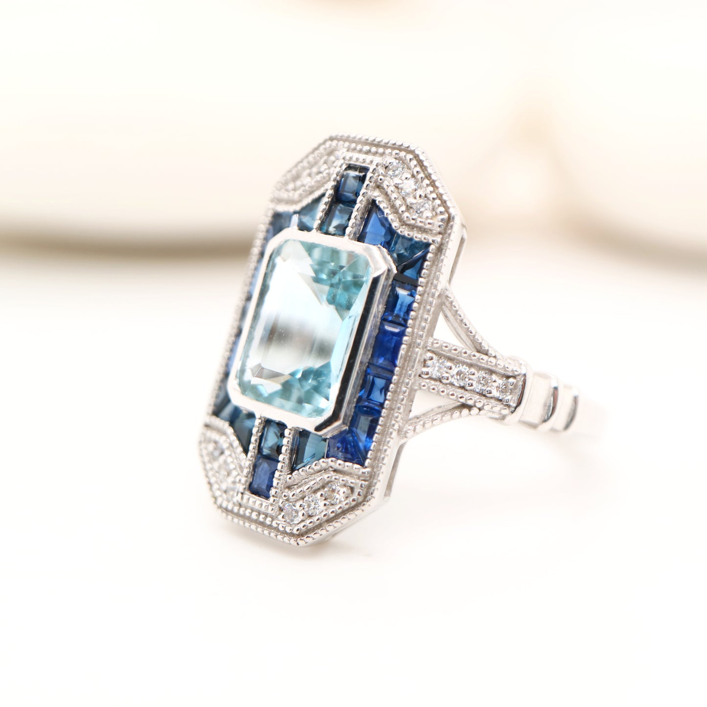 Art deco aquamarine cocktail ring with sapphire halo in white gold