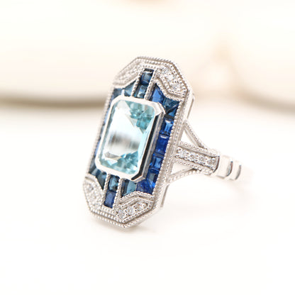 Art deco aquamarine cocktail ring with sapphire halo in white gold